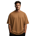 Man wearing a caramel Macbee oversized t-shirt on a white background