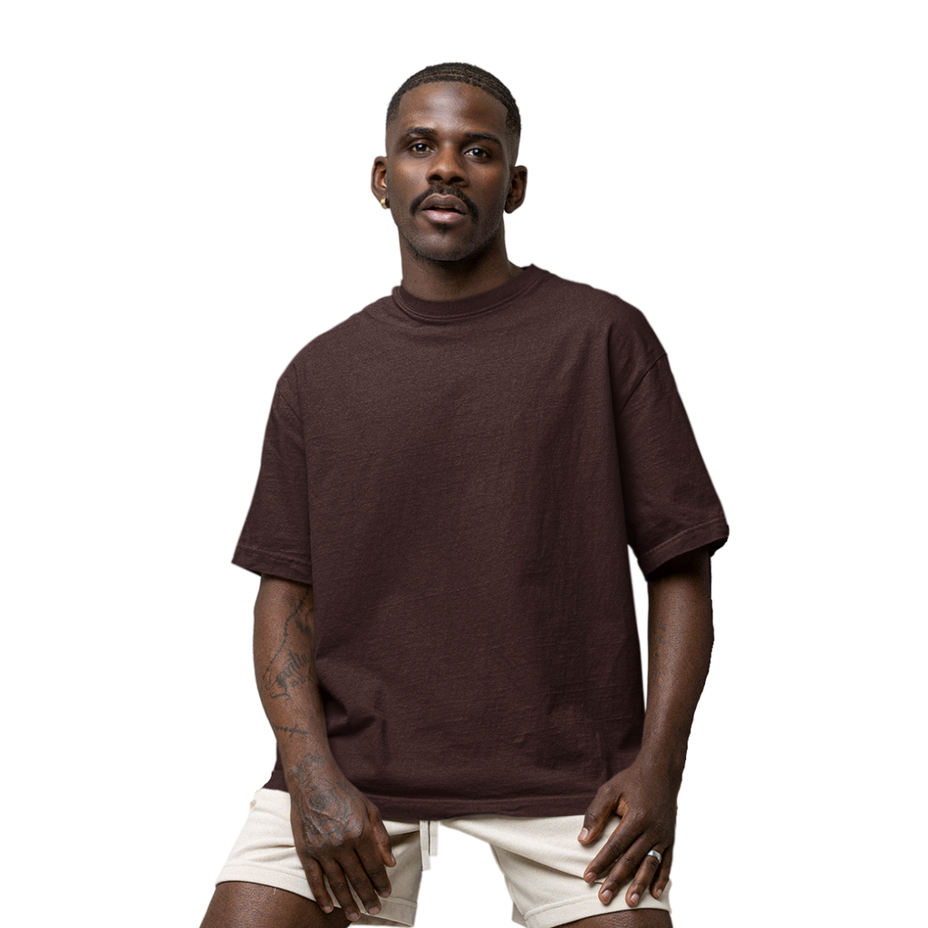 Man wearing a brown Macbee oversized t-shirt and beige shorts on a white background