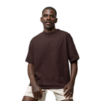 Man wearing a brown Macbee oversized t-shirt and beige shorts on a white background