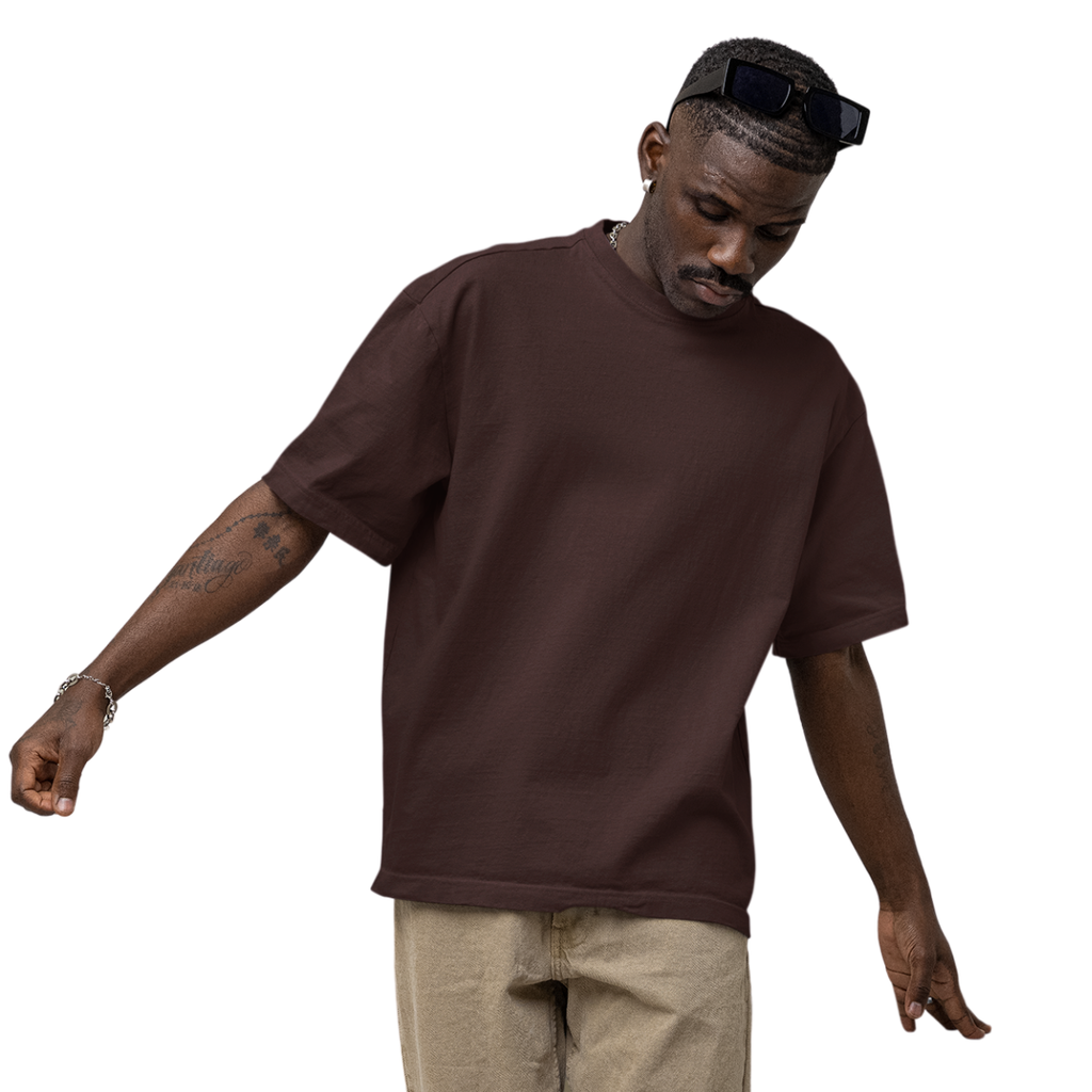 Man wearing a brown Macbee oversized t-shirt and beige pants on a white background