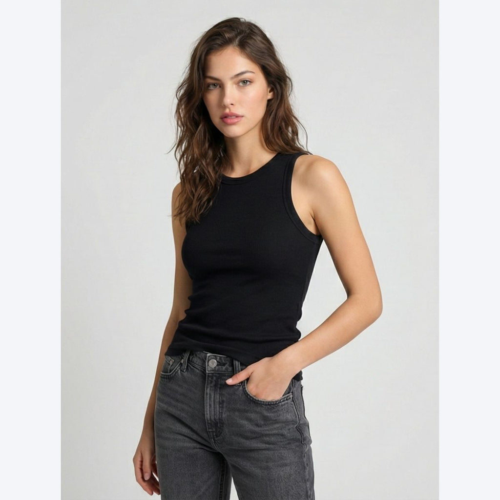 Woman wearing a black sleeveless top and gray jeans on a light gray background