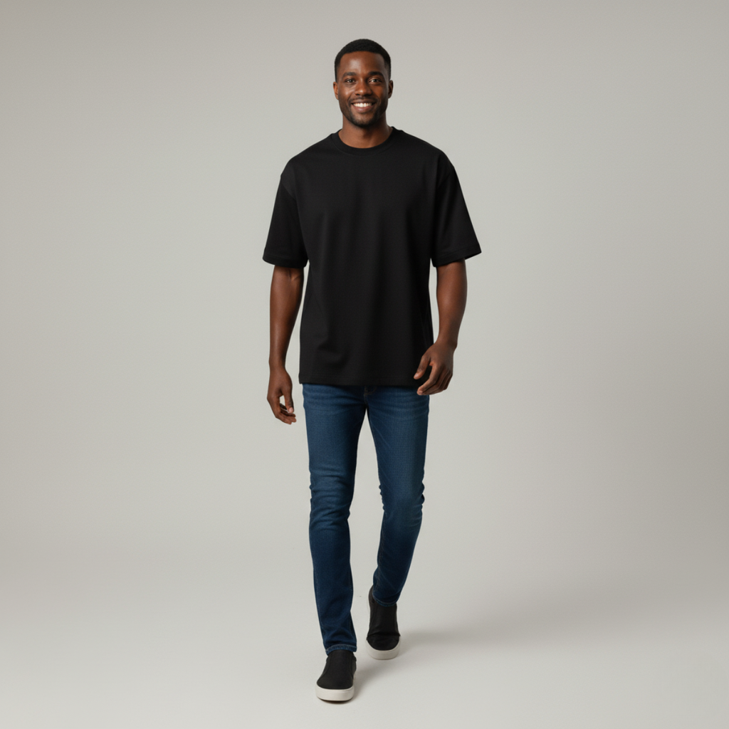 Man wearing a black t-shirt and blue jeans on a plain background