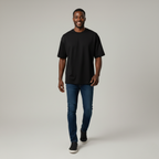 Man wearing a black t-shirt and blue jeans on a plain background