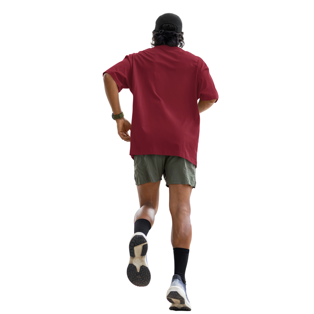 Person wearing a marsala Macbee oversized shirt and green shorts walking on a white background